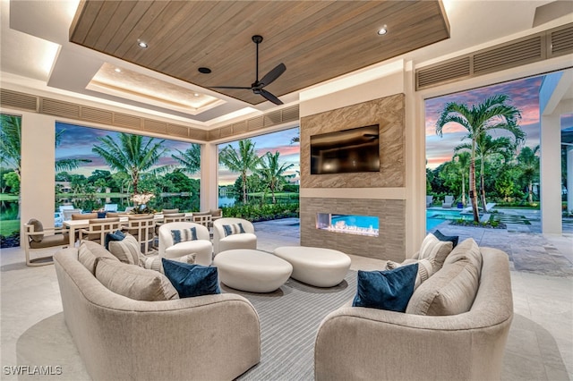 patio terrace at dusk featuring a multi sided fireplace and ceiling fan