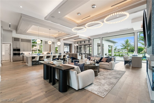 living room featuring light hardwood / wood-style flooring, a tray ceiling, and a chandelier