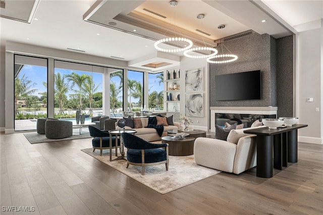 living room featuring a raised ceiling, a chandelier, and hardwood / wood-style flooring