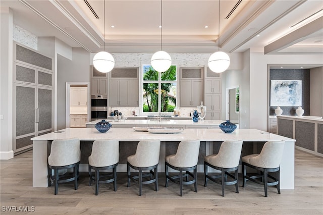 kitchen featuring a tray ceiling, gray cabinets, a large island, and hanging light fixtures