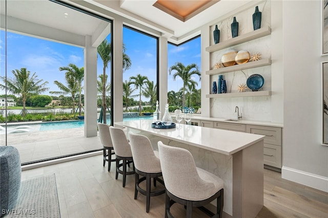 interior space featuring expansive windows, sink, a breakfast bar area, and light hardwood / wood-style flooring