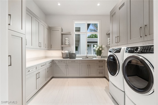 clothes washing area featuring cabinets, sink, and washing machine and dryer