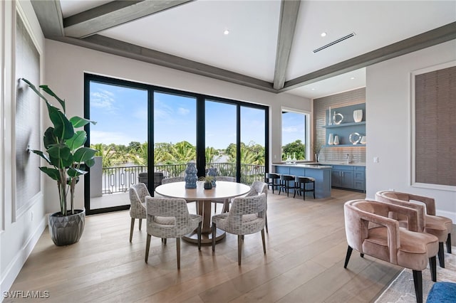 dining space with beam ceiling and light hardwood / wood-style floors