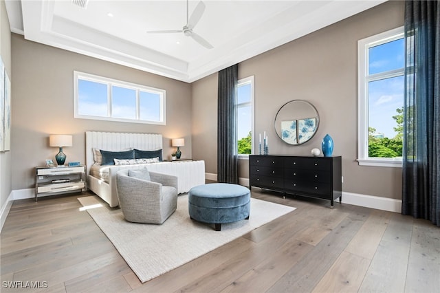 bedroom with a tray ceiling, ceiling fan, and light hardwood / wood-style floors