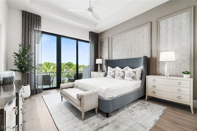 bedroom with hardwood / wood-style floors, ceiling fan, a raised ceiling, and access to outside