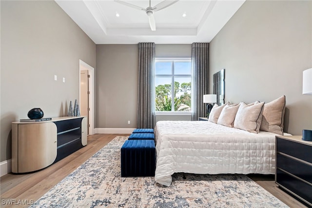 bedroom with hardwood / wood-style floors, ceiling fan, a raised ceiling, and ornamental molding