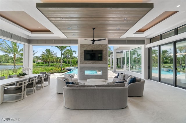 living room featuring a raised ceiling, ceiling fan, and wood ceiling