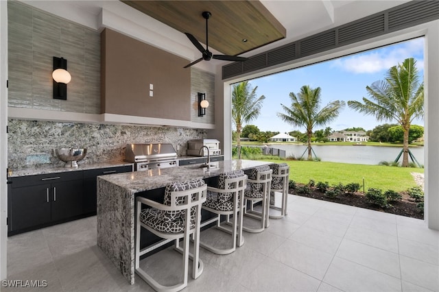 view of patio / terrace with ceiling fan, grilling area, area for grilling, a water view, and a wet bar