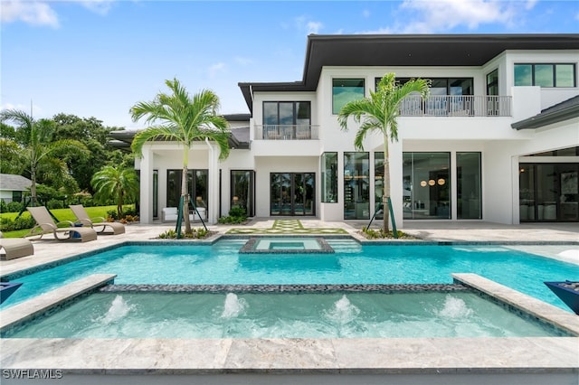 back of house with pool water feature, a balcony, a patio, and a pool with hot tub