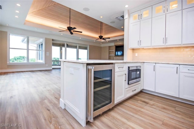 kitchen with beverage cooler, white cabinets, ceiling fan, and a raised ceiling