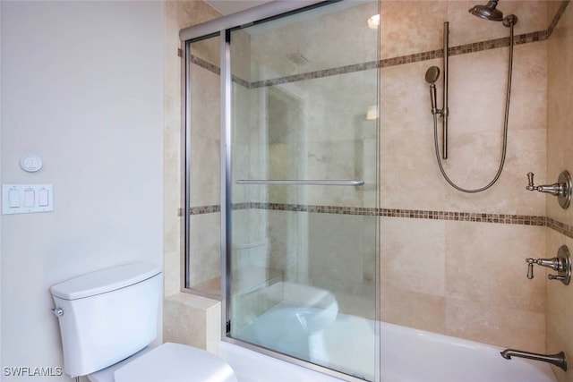 bathroom with combined bath / shower with glass door and toilet