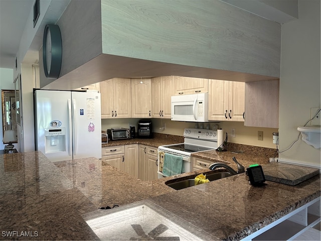 kitchen with white appliances, dark stone countertops, sink, and kitchen peninsula