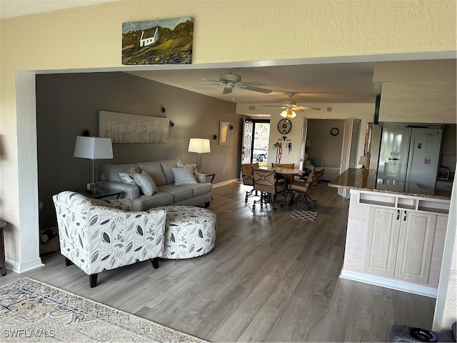 living room with ceiling fan and dark wood-type flooring