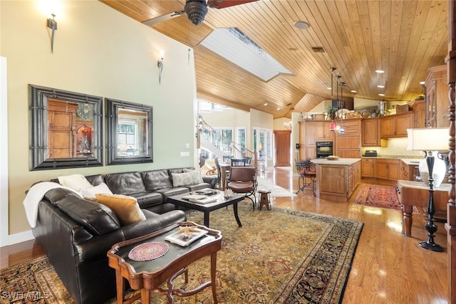 living room featuring ceiling fan, a skylight, wood ceiling, and light hardwood / wood-style flooring