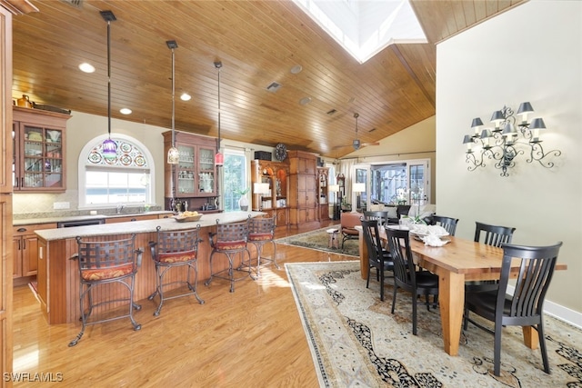 dining area with wood ceiling, light hardwood / wood-style floors, and lofted ceiling with skylight