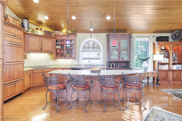 kitchen with wood ceiling, light hardwood / wood-style floors, a kitchen island, backsplash, and decorative light fixtures