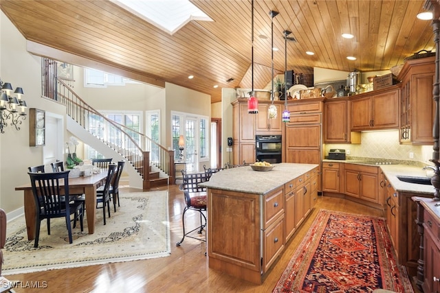 kitchen with wood ceiling, a kitchen island, pendant lighting, light wood-type flooring, and a skylight