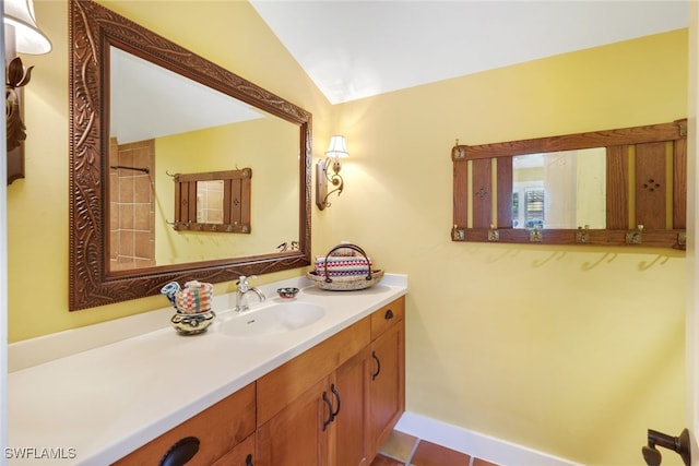 bathroom with a tile shower, lofted ceiling, vanity, and tile patterned flooring