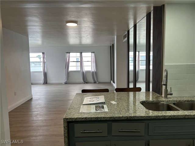 kitchen with light hardwood / wood-style floors, light stone countertops, and sink