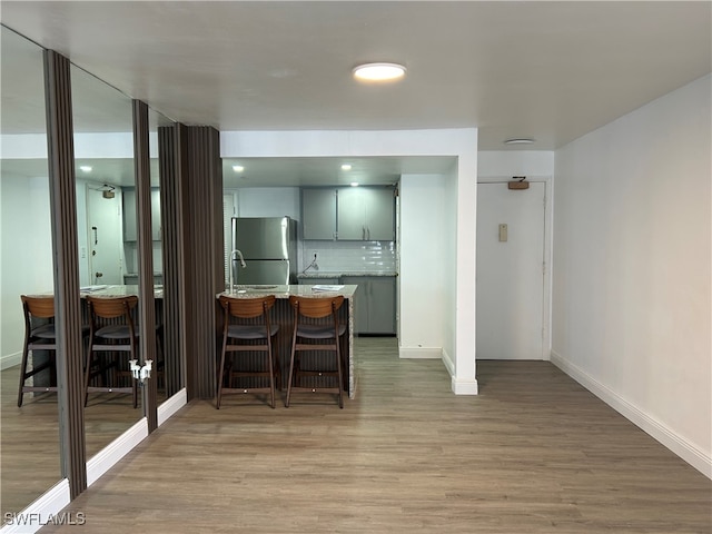 kitchen featuring stainless steel refrigerator, a breakfast bar area, hardwood / wood-style floors, and decorative backsplash