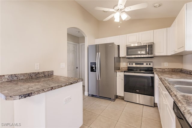 kitchen featuring vaulted ceiling, white cabinetry, light tile patterned floors, stainless steel appliances, and ceiling fan