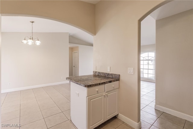 kitchen featuring white cabinets, decorative light fixtures, light tile patterned floors, and lofted ceiling