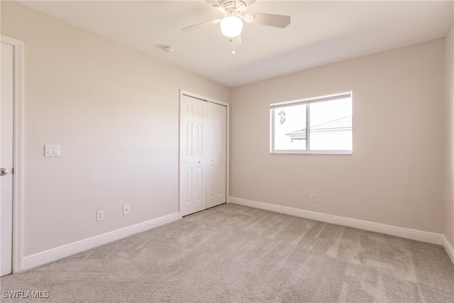 unfurnished bedroom featuring light carpet, a closet, and ceiling fan