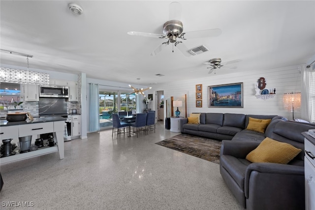 living room featuring ceiling fan with notable chandelier