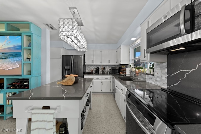 kitchen with white cabinets, backsplash, stainless steel appliances, sink, and a center island