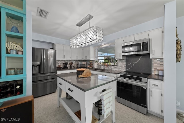 kitchen with decorative backsplash, white cabinetry, stainless steel appliances, and pendant lighting