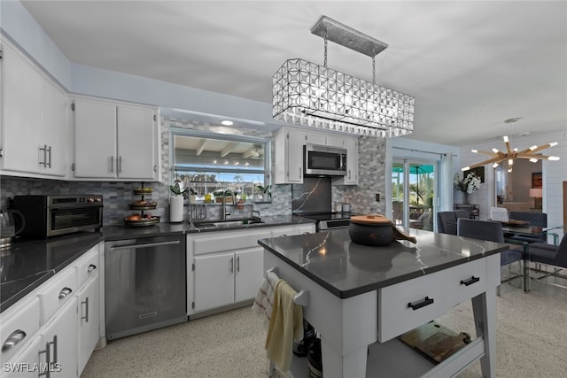 kitchen featuring sink, appliances with stainless steel finishes, a chandelier, and white cabinets