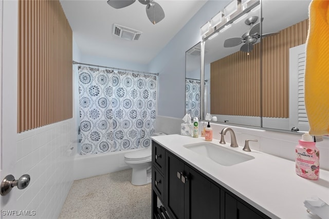 full bathroom with ceiling fan, tile walls, shower / bath combo with shower curtain, toilet, and vanity