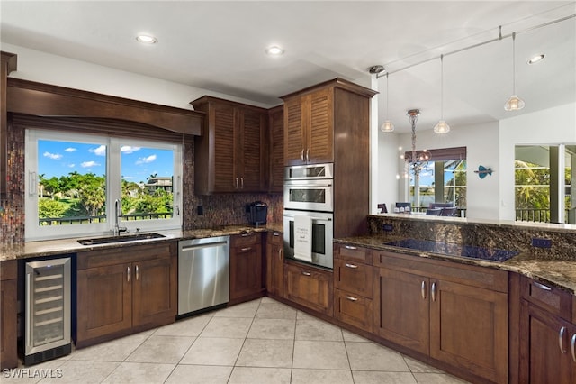 kitchen with dark stone countertops, plenty of natural light, beverage cooler, and appliances with stainless steel finishes