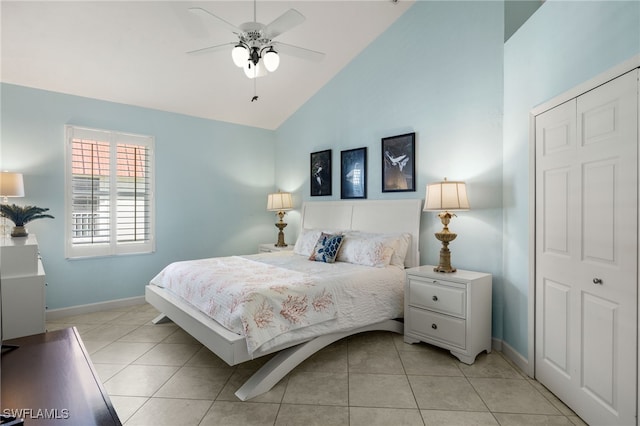 tiled bedroom with ceiling fan, high vaulted ceiling, and a closet