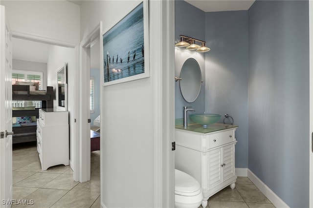 bathroom with toilet, vanity, and tile patterned floors