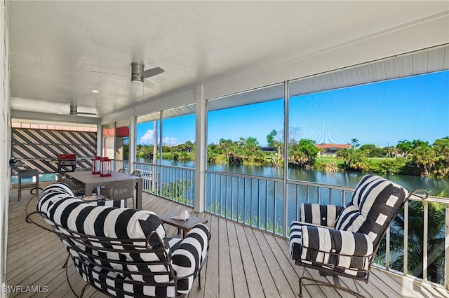 sunroom featuring ceiling fan and a water view