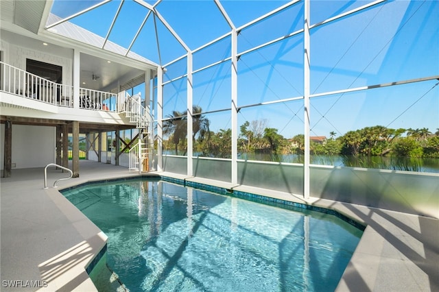 view of swimming pool with a lanai, a water view, and a patio