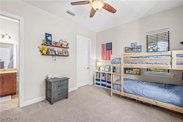 bedroom with light carpet, ensuite bath, and ceiling fan