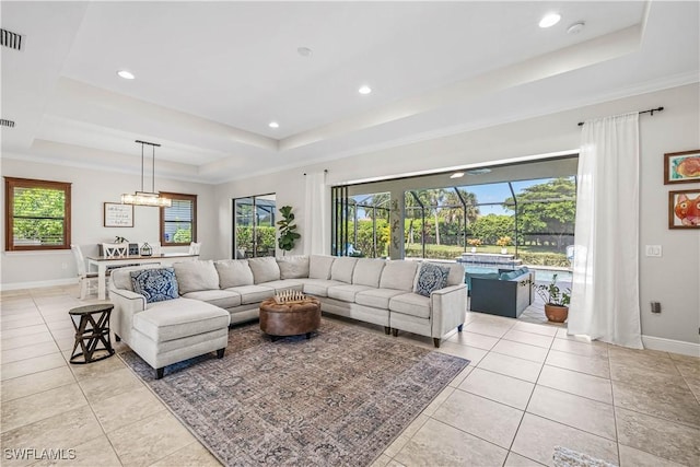 living room with a raised ceiling, a healthy amount of sunlight, and light tile patterned floors