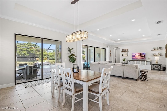 tiled dining area featuring crown molding and a raised ceiling