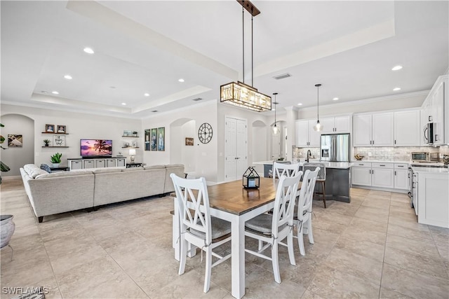 dining room featuring ornamental molding, sink, and a tray ceiling