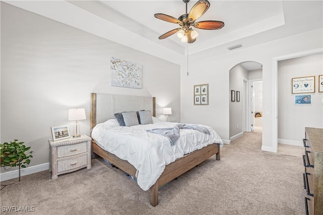 carpeted bedroom with ceiling fan and a tray ceiling