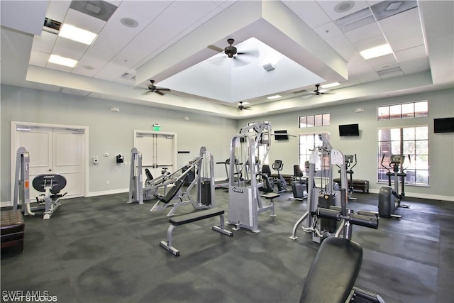 workout area with a raised ceiling, a towering ceiling, a drop ceiling, and ceiling fan