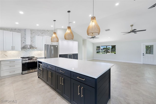 kitchen featuring hanging light fixtures, white cabinets, wall chimney exhaust hood, stainless steel appliances, and ceiling fan