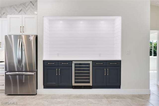 kitchen with light tile patterned floors, white cabinets, stainless steel refrigerator, and beverage cooler