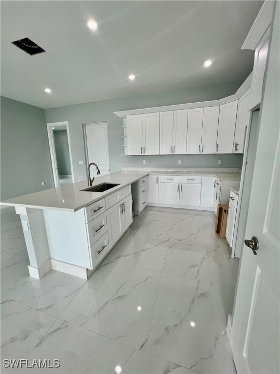 kitchen with kitchen peninsula, sink, and white cabinets