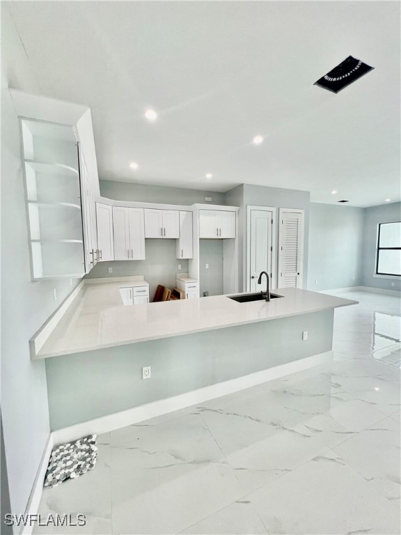 kitchen featuring white cabinets, kitchen peninsula, washer and clothes dryer, and sink