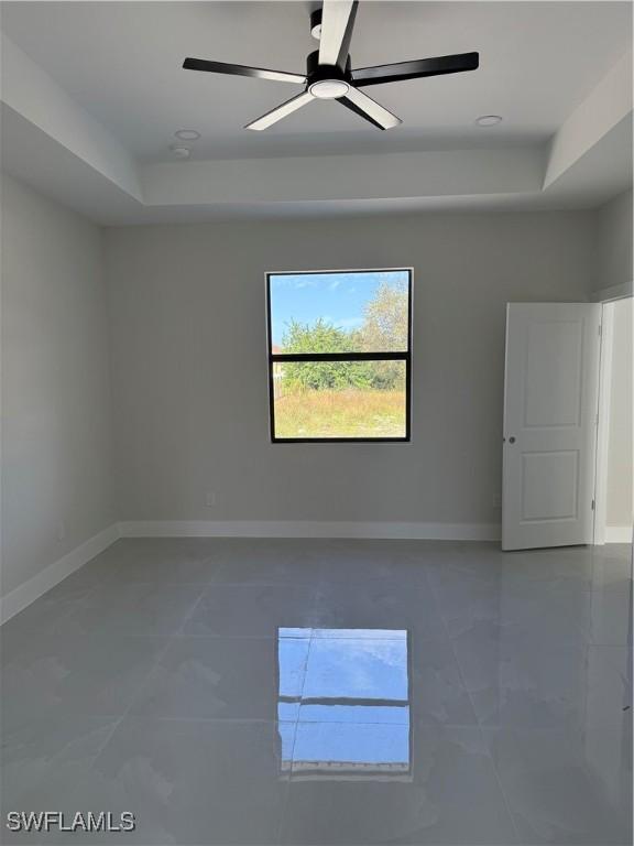 empty room with a raised ceiling and ceiling fan