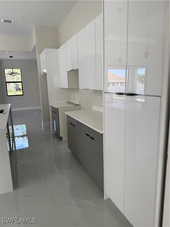 kitchen with hanging light fixtures, white cabinetry, white fridge, and gray cabinetry