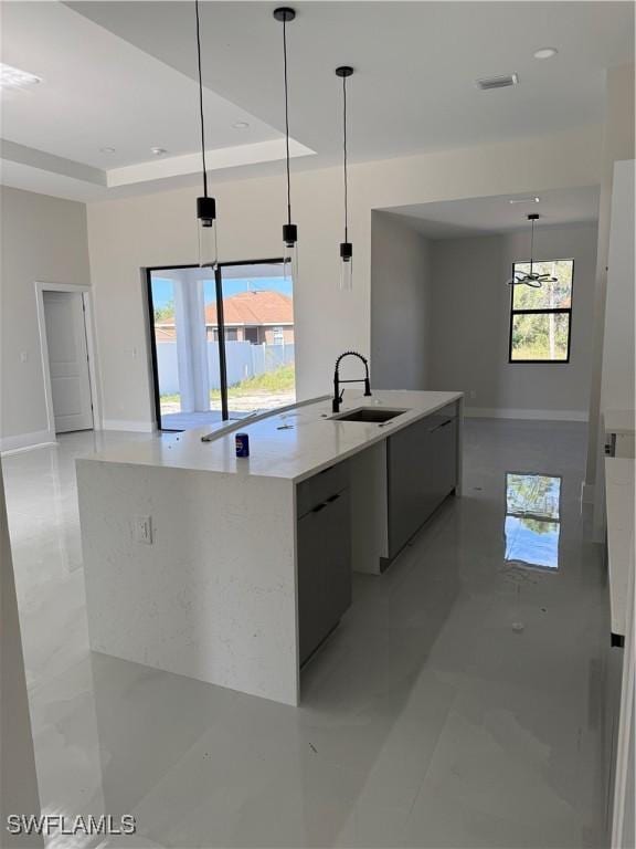 kitchen with a tray ceiling, a large island, decorative light fixtures, and sink